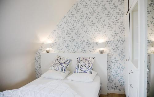 a bedroom with a white bed with blue and white pillows at La maison de Paul in Mittelwihr