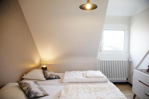 a bedroom with two beds with pillows and a window at La maison de Paul in Mittelwihr