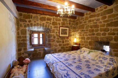 1 dormitorio con cama y pared de piedra en Castell d'Ogern, en Oliana