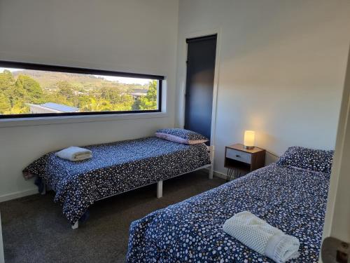 Cette chambre comprend deux lits et une grande fenêtre. dans l'établissement RESIDENTIAL 4 BEDROOM House, à Coffs Harbour