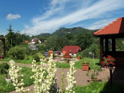 a garden with white flowers and a gazebo at Ferienpension Gabriele 61 in Kurort Gohrisch