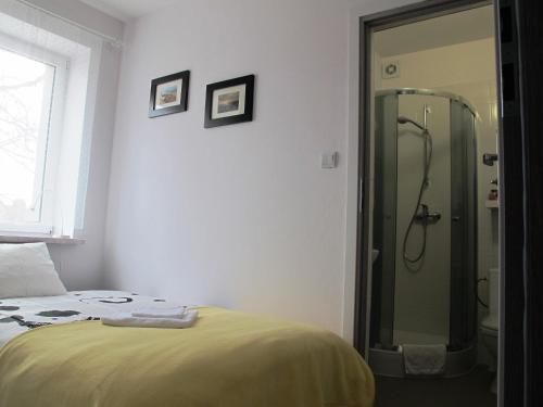 a bedroom with a shower and a bed with yellow sheets at Villa Marina in Augustów