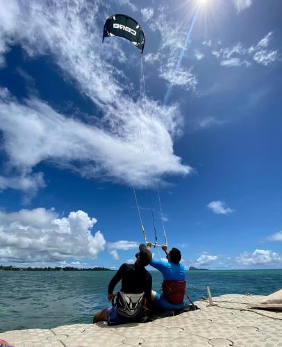 two people sitting on a pier flying a kite at Islands View - Mazor Beach Villas in Grand Gaube
