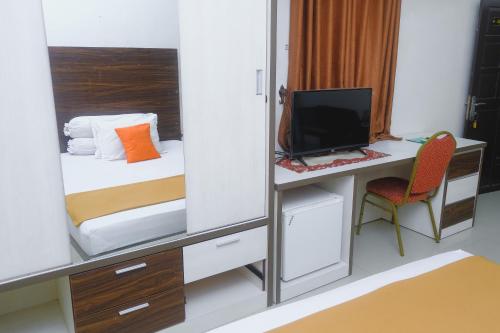 a bedroom with a bed and a desk with a computer at Lia Homestay Syariah Pettarani Makassar Mitra RedDoorz in Makassar