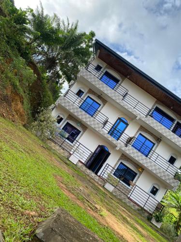 a white building with blue windows on a hill at Prestige beach résidence in Kribi