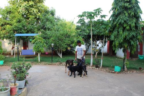 a man standing with two dogs in a yard at "Priyadarshi Villa" Free pickup in ac car from Jasidih Railway station or Deoghar Airport in Deoghar
