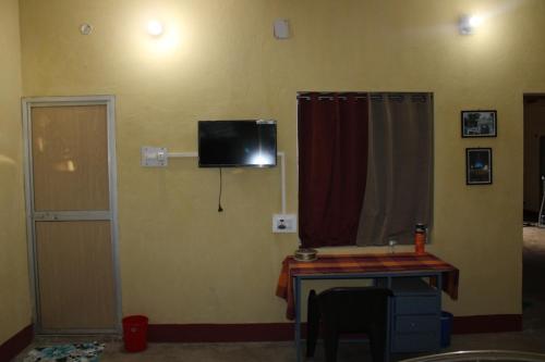 a room with a table and a television on the wall at "Priyadarshi Villa" Free pickup in ac car from Jasidih Railway station or Deoghar Airport in Deoghar