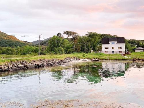 a white house on the side of a river at 8 person holiday home in Bølandet-By Traum in Røyra