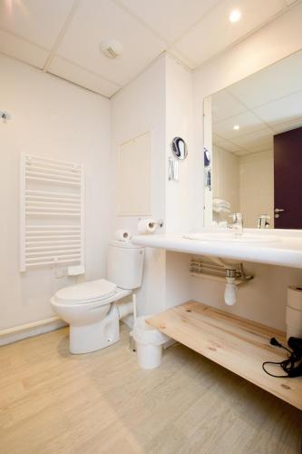 une salle de bain blanche avec des toilettes et un lavabo dans l'établissement Grand studio avec climatisation, balcon proche gare centre ville, à Lourdes