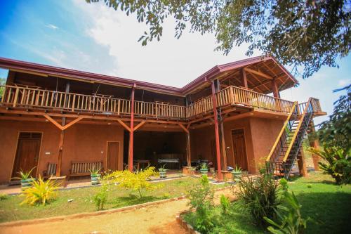 a large house with a deck and a yard at Jungle Hut Resort Sigiriya in Sigiriya