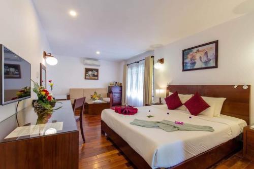 um quarto de hotel com uma cama grande e uma mesa em Vinh Hung Riverside Resort & Spa em Hoi An