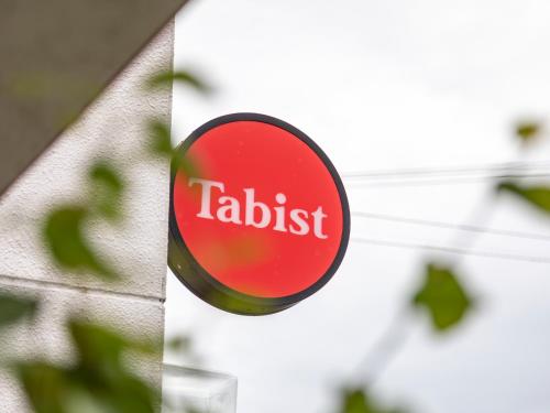 a sign on a building with the name of a retailer at Tabist Motodai Business Hotel Kanonji in Kanonji