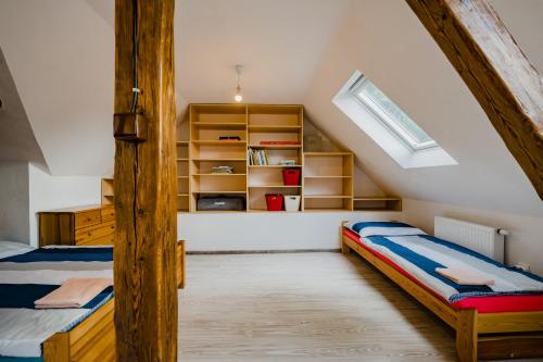 a attic bedroom with two beds and a window at Na Želivce chalupa Marie in Želiv