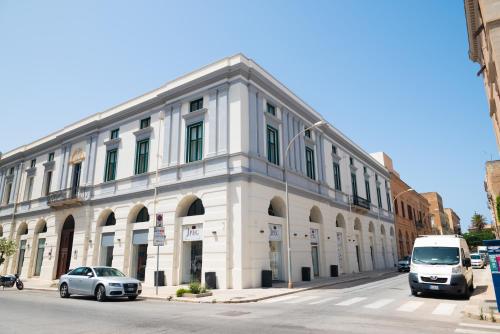 a white building with cars parked in front of it at Historico Loft & Rooms Palazzo Adragna XIX in Trapani