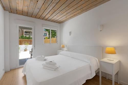 a white bedroom with a bed and a window at Apartamentos Sureda in Canyamel