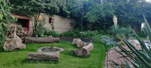 a garden with logs and rocks in the grass at Ecolodge Tilburg met zwembad in groene oase bij centrum in Tilburg