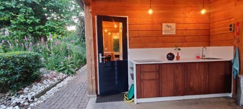 uma porta que leva a uma cozinha numa casa de madeira em Ecolodge prive sauna, prachtige tuin, jacuzzi en warm zwembad em Tilburg