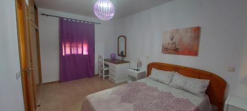 a bedroom with a bed and a purple curtain at El cortijo de Valverde in Lajares