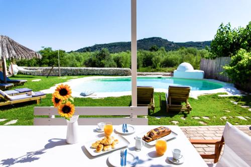 a table with food on it next to a swimming pool at Sonio Villas - Que Bella Collection in Plataniás