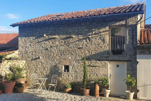 ein Steinhaus mit einer weißen Tür und einigen Pflanzen in der Unterkunft Gite Coquille Saint Jacques in Nanteuil-en-Vallée