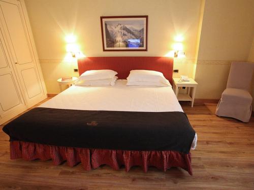 a bedroom with a large bed with a red headboard at Grand Hotel Royal E Golf in Courmayeur