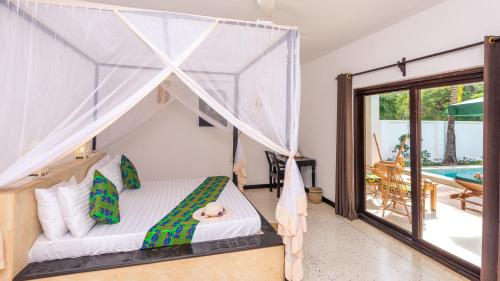 a bedroom with a canopy bed with a dog laying on it at Daima Villas in Jambiani