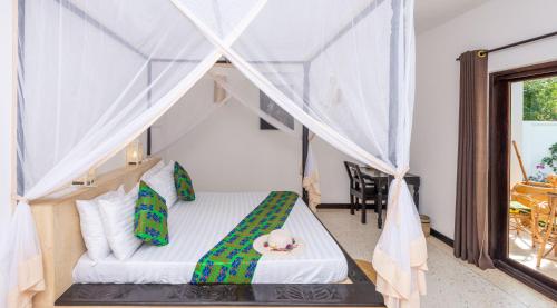 a bedroom with a bed with a canopy at Daima Villas in Jambiani