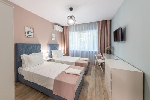 a hotel room with two beds and a desk at Great Location Apartment in Varna City