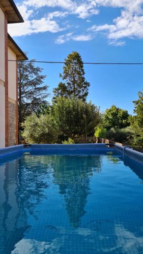 una piscina con agua azul frente a una casa en VAL D'ORCIA DELUXE 1 ELEGANTE CASA immersa nel verde con WiFi, giardino e parcheggio, en San Giovanni dʼAsso
