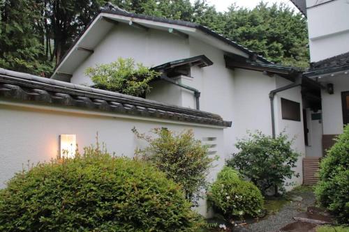 a white house with plants on the side of it at Yamaguchi House Villa,Historic Japanese Room with Onsen in Miyanoshita