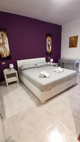 1 dormitorio con 1 cama grande y pared morada en Mare e Città, en Selargius