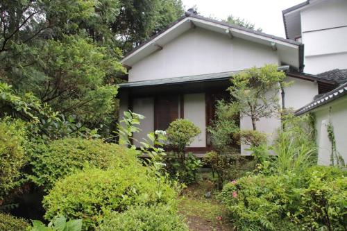 a white house with bushes in front of it at Yamaguchi House Villa,Historic Japanese Room with Onsen in Miyanoshita
