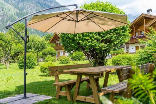 a wooden picnic table with an umbrella in the grass at Appartamento Bucaneve in Predazzo