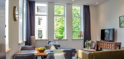 sala de estar con sofá, sillas y ventanas en Spoorzicht Long Stay Apartments, en Loppersum