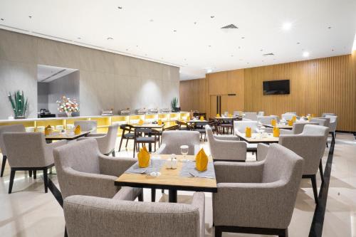 un restaurante con mesas y sillas y TV en Golden Tulip Pontianak en Pontianak