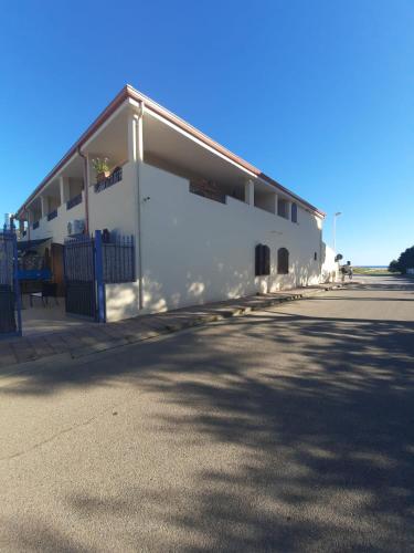 a white building with a roof on a street at Hotel Villa del Mare Solanas in Solanas