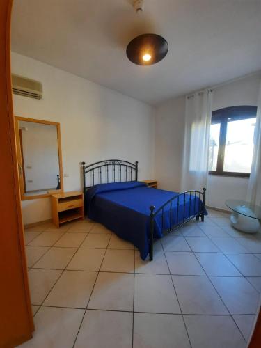 a bedroom with a blue bed and a mirror at Hotel Villa del Mare Solanas in Solanas