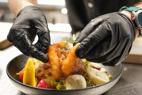 a person wearing black gloves preparing a bowl of food at Comfort Hotel Kista in Stockholm