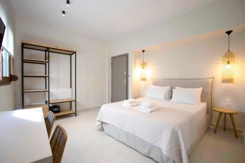 a bedroom with a white bed and a table at Palm Residences in Pefkohori