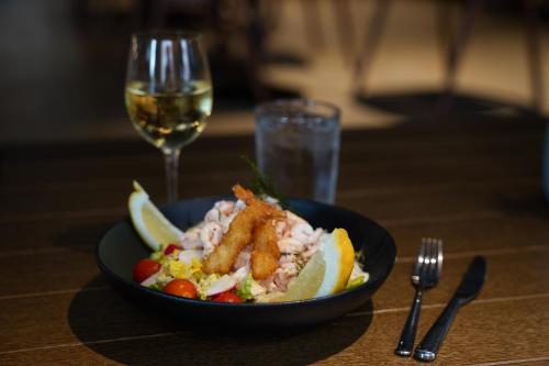 a bowl of food with shrimp and a glass of wine at Comfort Hotel Kista in Stockholm