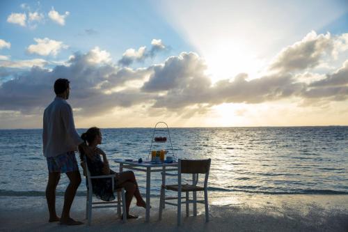 a man and a woman sitting at a table on the beach at Solana Beach Mauritius - Adults Only in Belle Mare