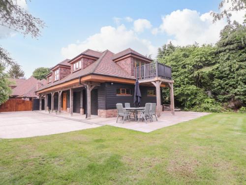 a house with a deck and a table in the yard at The Barn at Mulberry Lodge in Maidstone
