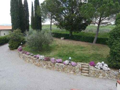 a stone retaining wall with flowers in a yard at Agriturismo Il Poggio Rosso di Maremma in Manciano