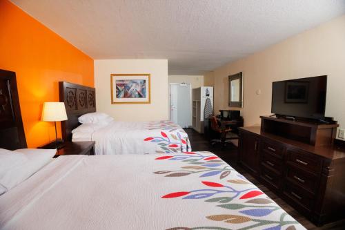 a hotel room with two beds and a flat screen tv at Garnet Inn & Suites, Orlando in Orlando
