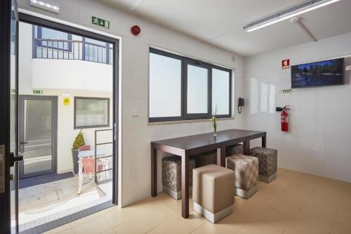 an empty room with a table and some windows at Suites & Hostel Cidade Aveiro in Aveiro