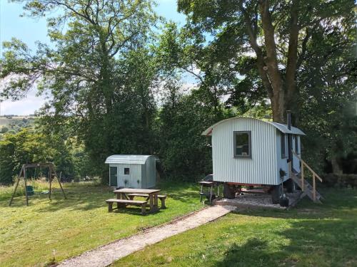 a shed and a picnic table and a playground at orchard meadow shepherd huts leek-buxton-ashbourne in Upper Elkstone