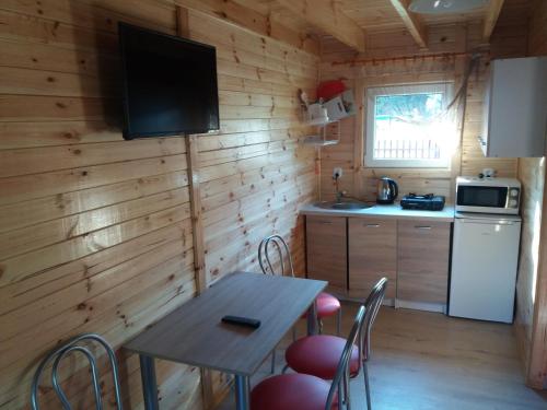 a kitchen with a table and chairs in a cabin at Domki i pokoje ,,Pod Palmami" w centrum in Okuninka