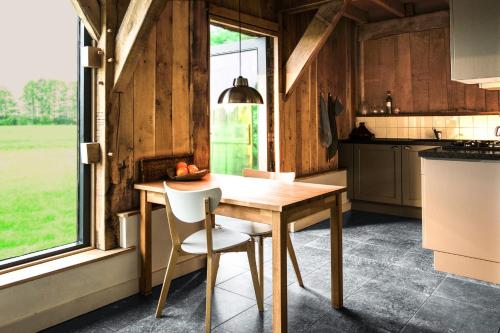 a kitchen with a wooden table and chairs and a window at Wilmsboo in Nieuw-Schoonebeek