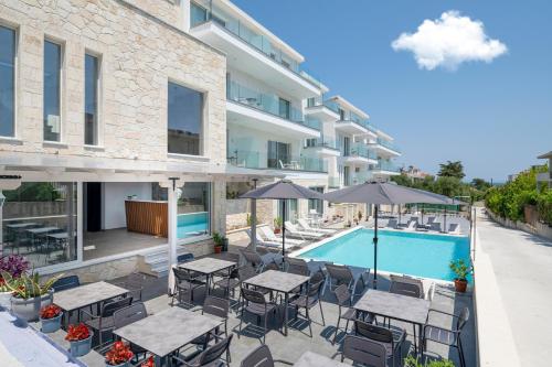 a patio with tables and umbrellas next to a swimming pool at Hanioti Central Hotel in Hanioti