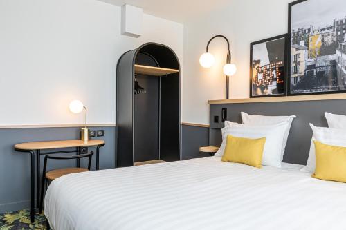 a bedroom with a large bed with yellow pillows at Best Western M-Treize Paris Asnieres in Asnières-sur-Seine